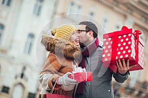 Couple dressed in winter clothing holding gift boxes outdoor