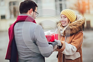 Couple dressed in winter clothing holding gift boxes outdoor