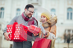 Couple dressed in winter clothing holding gift boxes outdoor