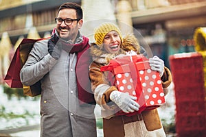 Couple dressed in winter clothing holding gift boxes outdoor
