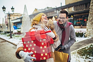 Couple dressed in winter clothing holding gift boxes outdoor