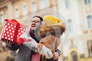 Couple dressed in winter clothing holding gift boxes outdoor