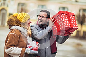 Couple dressed in winter clothing holding gift boxes outdoor