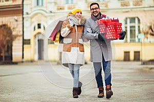 Couple dressed in winter clothing holding gift boxes and shopping bags outdoor