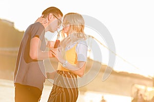 couple drinking beverage with two plastic straws from one bottle on river beach