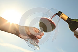 A couple drinking a bottle of red wine outside