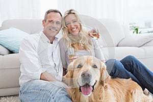 Couple drinking champagne with their dog in front of them