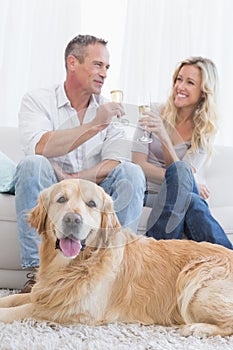 Couple drinking champagne with their dog in front of them