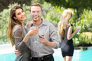 Couple drinking cocktail by swimming pool at party