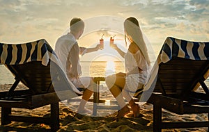 Couple drinking cocktails on beach during vacation or honeymoon in tropics