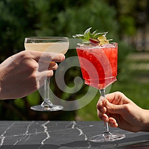 couple drinking cocktails during home party on a green lawn in their garden. Concept of relationship.Close-up on hands