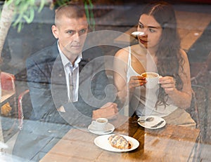 Couple drinking coffee with croissant in cafe
