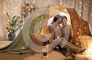 Couple drinking coffee or tea in kids tent at home