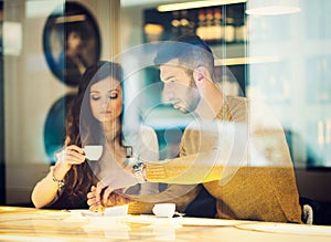 Couple drinking an espresso. Reflected between the window