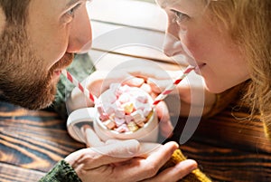 Couple drinking hot chocolate cocoa with heart shaped marshmallow on top