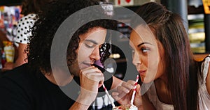 Couple drinking smoothie together with straw in pub