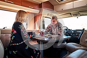Couple drinking tea sitting inside of recreational vehicle