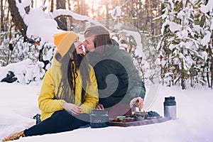 Couple drinks tea in a winter forest