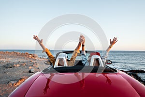 Couple driving convertible car near the ocean