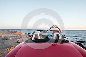 Couple driving convertible car near the ocean