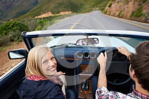 Couple, driving and convertible steering wheel on mountain from behind for vacation happy, adventure or holiday. Man