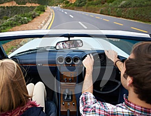 Couple, driving and convertible steering wheel on road from behind on mountain for vacation, adventure or holiday. Man