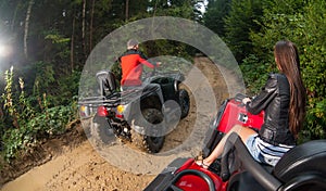 Couple driving four-wheelers ATV offroad