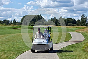 Couple driving golf cart across golf club fields