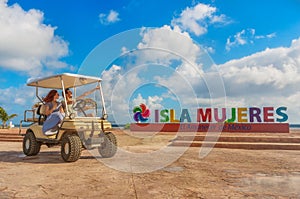 Couple driving a golf cart at tropical beach on Isla Mujeres, Mexico