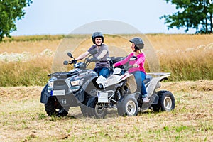 Couple driving off-road with quad bike or ATV