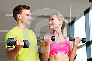 Couple with dumbbells exercising in gym