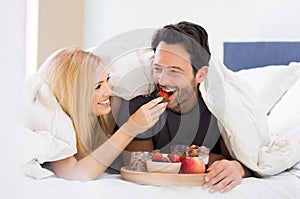 Couple eating breakfast on bed