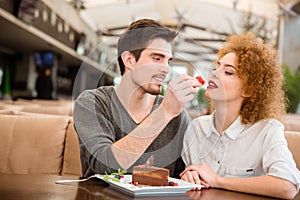 Couple eating cake with strawberry in restaurant