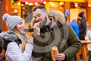 couple eating czech Trdelnik on Christmas fair in Wroclaw, Poland