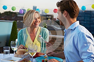 Couple Eating Evening Meal On Rooftop Terrace