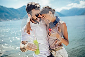 Couple eating fruit on the beach- summer party with friends and healthy food concept