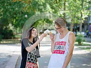 Couple eating ice cream in a park. Boyfriend and girlfriend on a blurred natural background. Dating concept. Copy space.