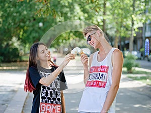 Couple eating ice cream in a park. Boyfriend and girlfriend on a blurred natural background. Dating concept. Copy space.