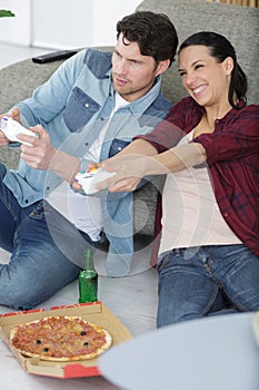 couple eating pizza and playing computer game home