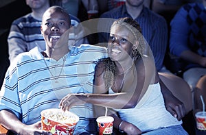 Couple Eating Popcorn While Watching Movie In Theatre