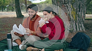 Couple eating romantic picnic in forest. Young pair tasting food on blanket.