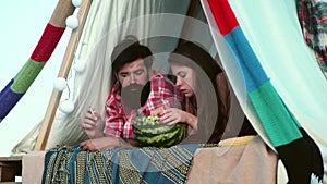 Couple eating watermelon in tent camping. Portrait of passionate lovers in cozy tent for couple in love on nature