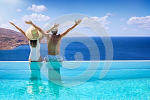 A couple at the edge of a swimming pool enjoying the view to the mediterranean sea