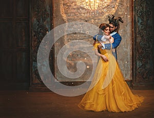 Couple embrace in room old castle. Happy beauty woman fantasy princess in yellow dress and guy is enchanted beast, horns