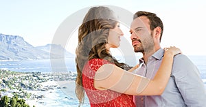 Couple embracing against blurry coastline with flare