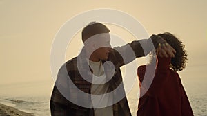 Couple embracing on beach at sunrise. Woman and man kissing on ocean shore