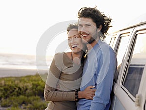 Couple Embracing By Campervan On Beach