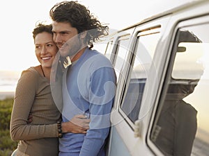 Couple Embracing By Campervan On Beach