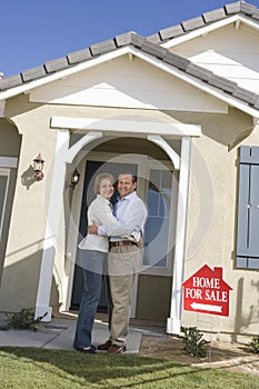 Couple Embracing In Front Of House For Sale