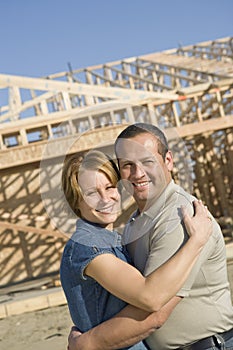 Couple Embracing In Front Of Incomplete House